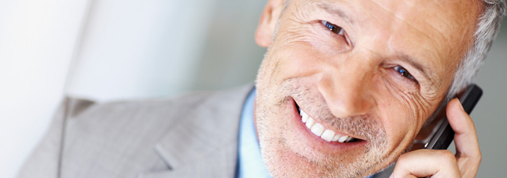 A smiling older man talking on the phone